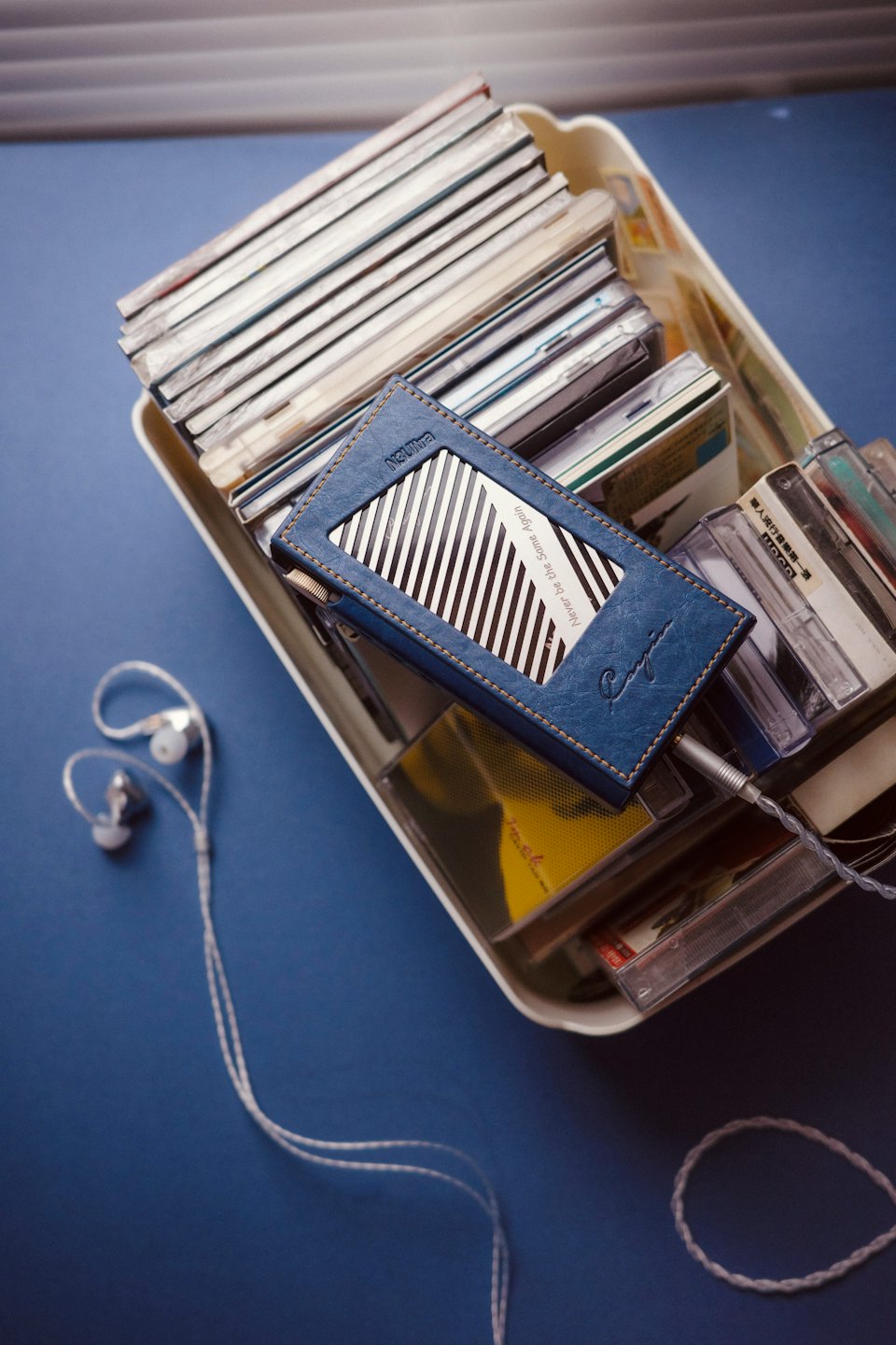 Blue digital audio player with connected earphones resting on vintage media.